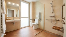 Baño accesible con ducha enrasada antideslizante, barras de apoyo y asiento abatible para movilidad reducida